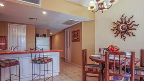 A compact kitchen with a central island, bar stools, and a dining table with chairs. - Princesa C-104 Barefoot Bumblebee Newly Renovated Ocean View Condo (Puerto Penasco)