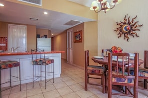 A compact kitchen with a central island, a dining area with a round table and chairs, and a decorative wall piece.