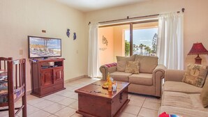 A living room with a television, sofa, and coffee table. - Princesa C-104 Barefoot Bumblebee Newly Renovated Ocean View Condo (Puerto Penasco)