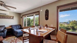 A dining area with a wooden table, chairs, and a view of greenery outside.