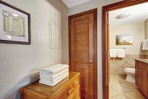 Ein Badezimmer mit Holztür, einem gerahmten Zertifikat an der Wand und einem Stapel Handtücher auf einer Holzkommode.