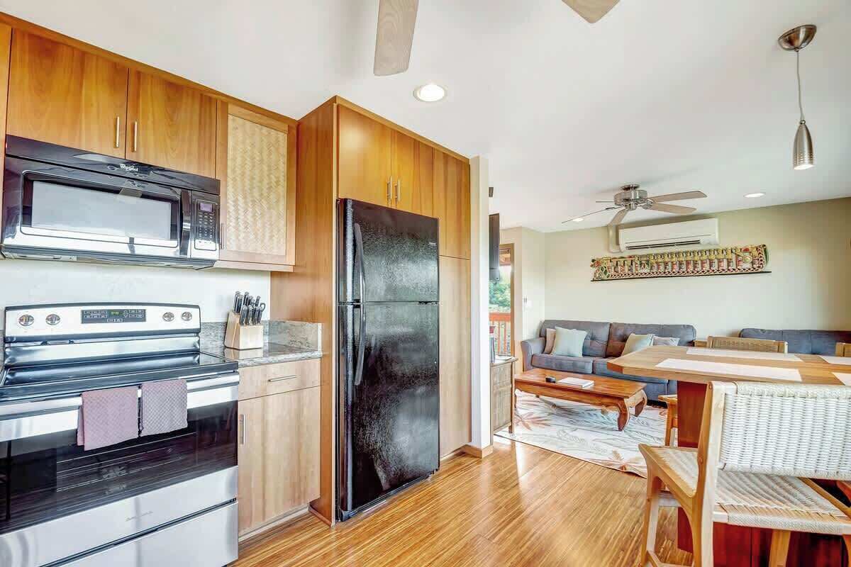 Una cocina moderna con armarios de madera, un refrigerador negro y un microondas.