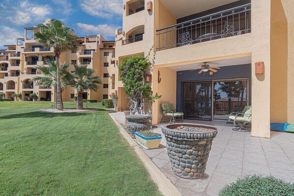 A multi-story hotel with outdoor seating, palm trees, and a stone planter.
