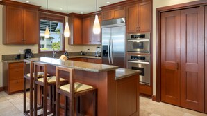 A modern kitchen with wooden cabinets, stainless steel appliances, and a bar area with stools.