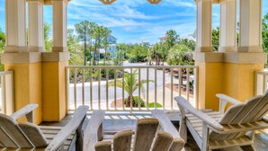 A covered outdoor seating area with wooden chairs and a view of a residential neighborhood.