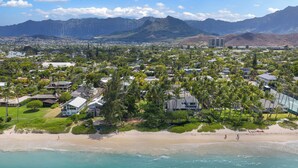 Un pueblo costero con zonas residenciales, una playa y montañas al fondo.