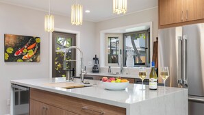 Una cocina moderna con una isla grande, electrodomésticos de acero inoxidable e iluminación colgante.