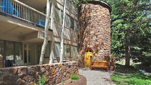 A building with a stone tower, a wooden door, and a bench outside. - Stunning Ski-In Ski-Out Condo/Private Hot Tub/Recently Updated (Dillon)