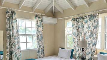 A room with two beds, a window, an air conditioning unit, and a lamp.