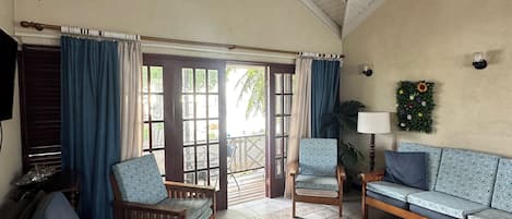 A spacious living area with a ceiling fan, a sofa, a patterned armchair, a coffee table, and a sofa set.