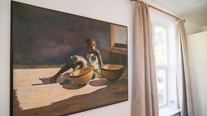 A painting of a child with bowls on a table, a window with curtains, and a radiator.
