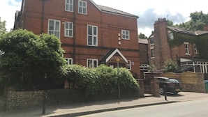 A two-story brick building with multiple windows, a gated entrance, and a parked car.