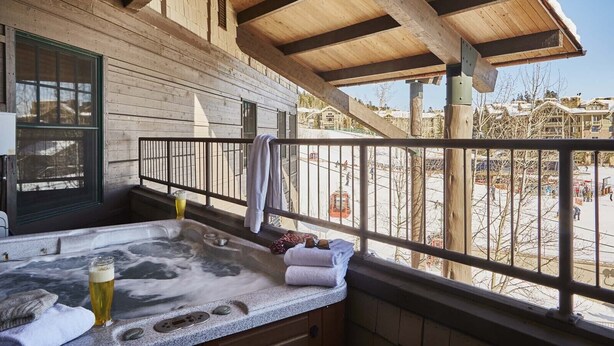 Un balcon en bois avec un jacuzzi, des serviettes et une bouteille de bière.