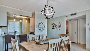 Un comedor con mesa y sillas de madera, una araña y un adorno en la pared.