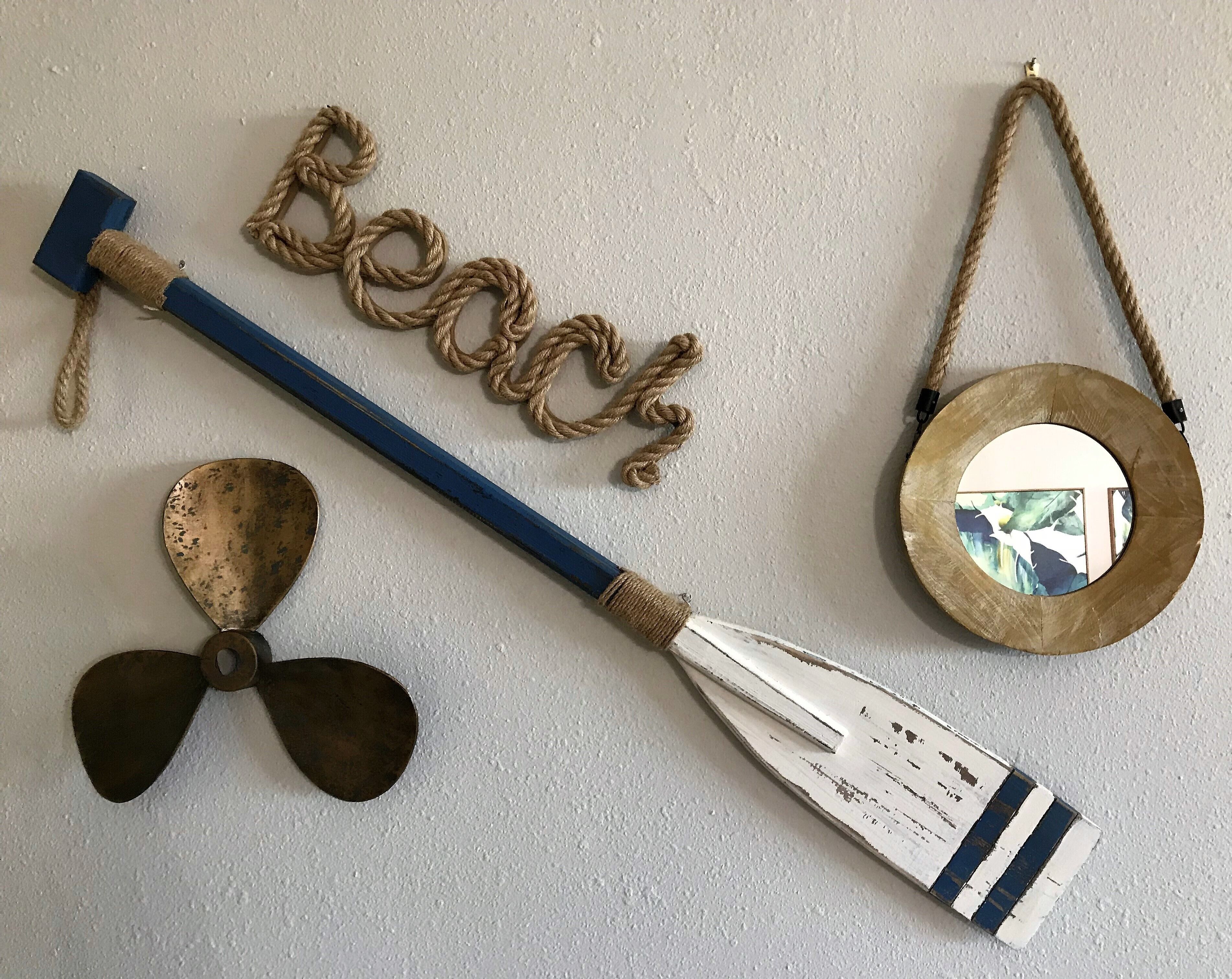 A nautical-themed decor with a rope, a wooden paddle, and a round mirror.