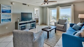 Una sala de estar con televisión, sofá, sillón y un balcón con vistas.