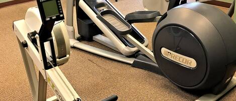 Ett gym med konditionsmaskiner, en motionscykel och en roddmaskin.