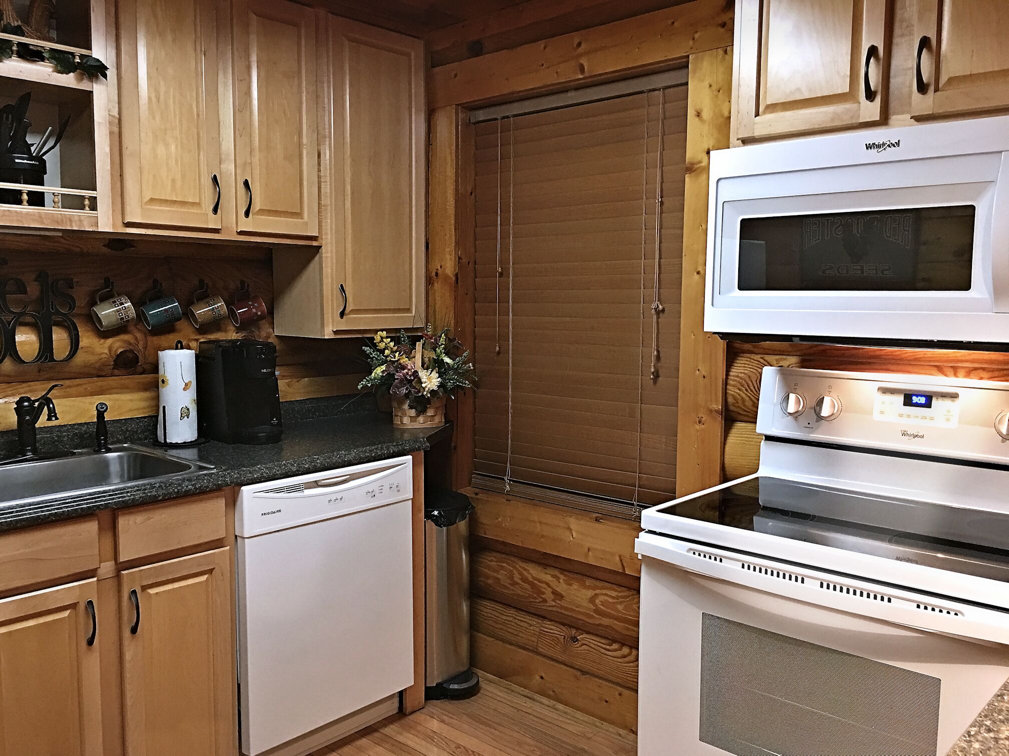 A compact kitchen with wooden cabinets, a built-in microwave, a stove, and a dishwasher.