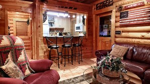 A cozy log cabin interior with a dining area, a red sofa, and a leather couch.