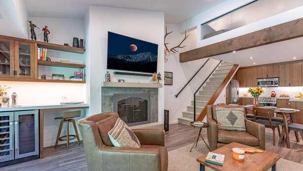 A modern living space with a fireplace, a kitchen, and a staircase.