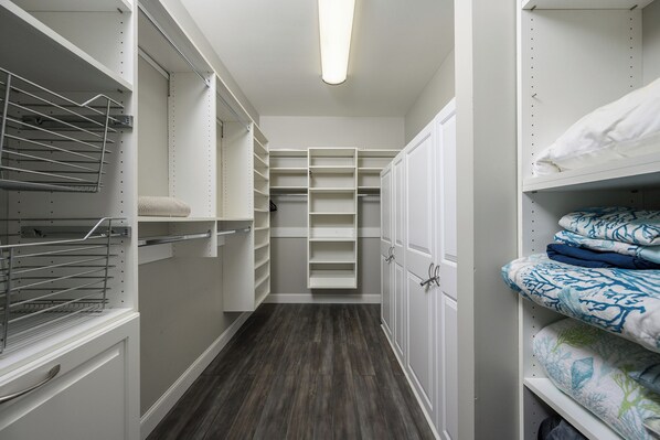 Un vestidor amplio con estantes abiertos, espacio para colgar ropa y una cama con ropa de cama estampada.