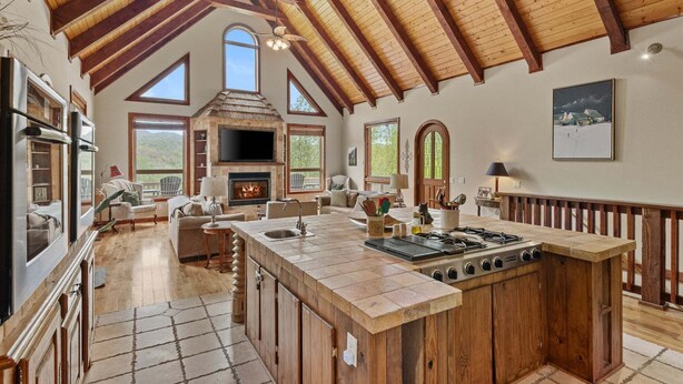 A spacious kitchen with a large island, a fireplace, and a dining area with a view. - Stoneledge Manor - Creek with Pond - Mountain Views - Pool Table (Banner Elk)
