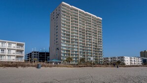 Korkea hotellirakennus, jossa on useita parvekkeita, ja joka sijaitsee hiekkarannalla. Taustalla näkyy muita rakennuksia.