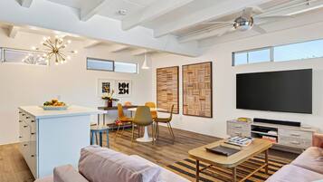 Un espacio de estar moderno con comedor, sofá, mesa de centro y televisor.