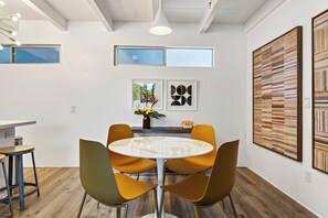 Un interior moderno con una mesa redonda, cuatro sillas y obras de arte en las paredes.