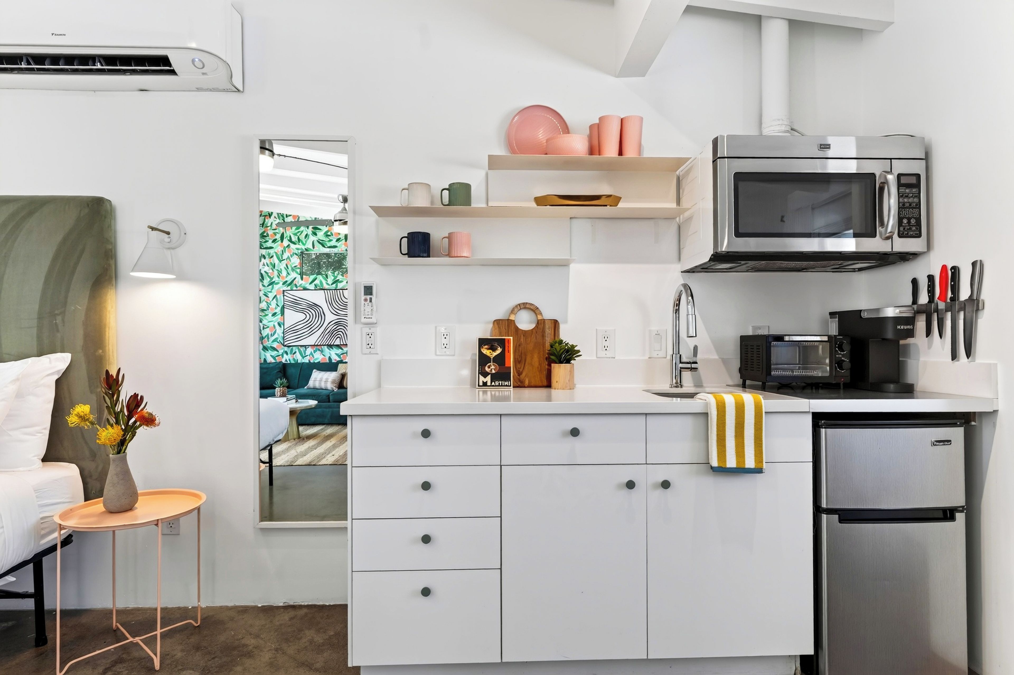 Una kitchenette compacta con microondas, tostadora y refrigerador.