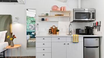 Una kitchenette compacta con microondas, tostadora y refrigerador.