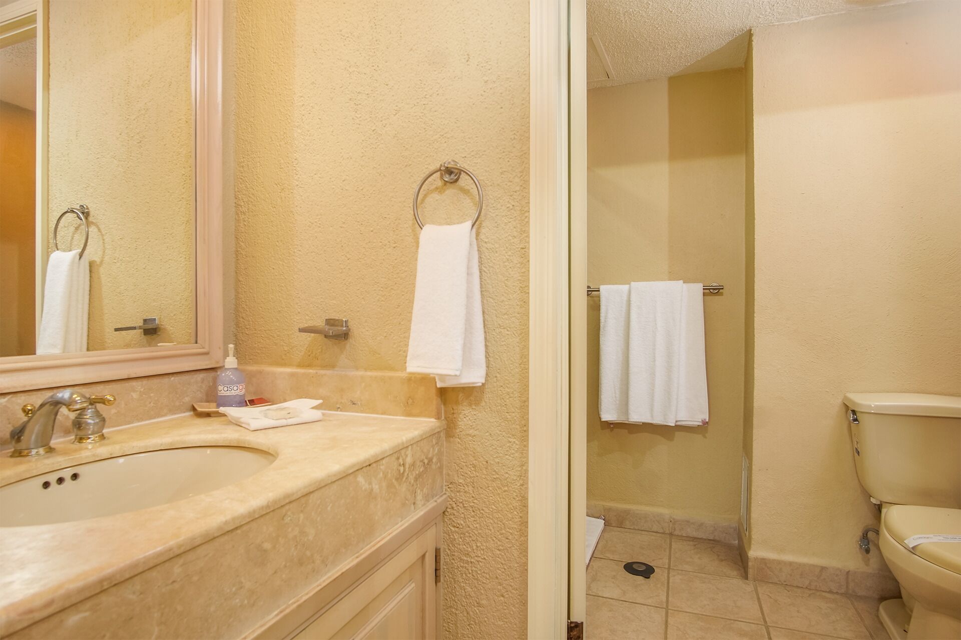 Une salle de bain avec un lavabo, un miroir et des toilettes.