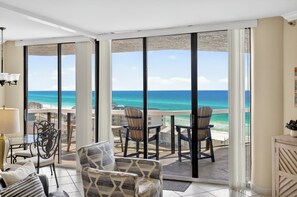 Un balcone con vista sull'oceano, arredato con sedie e un tavolo.