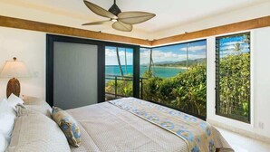 Un dormitorio con una cama grande, un ventilador de techo y vista al océano.