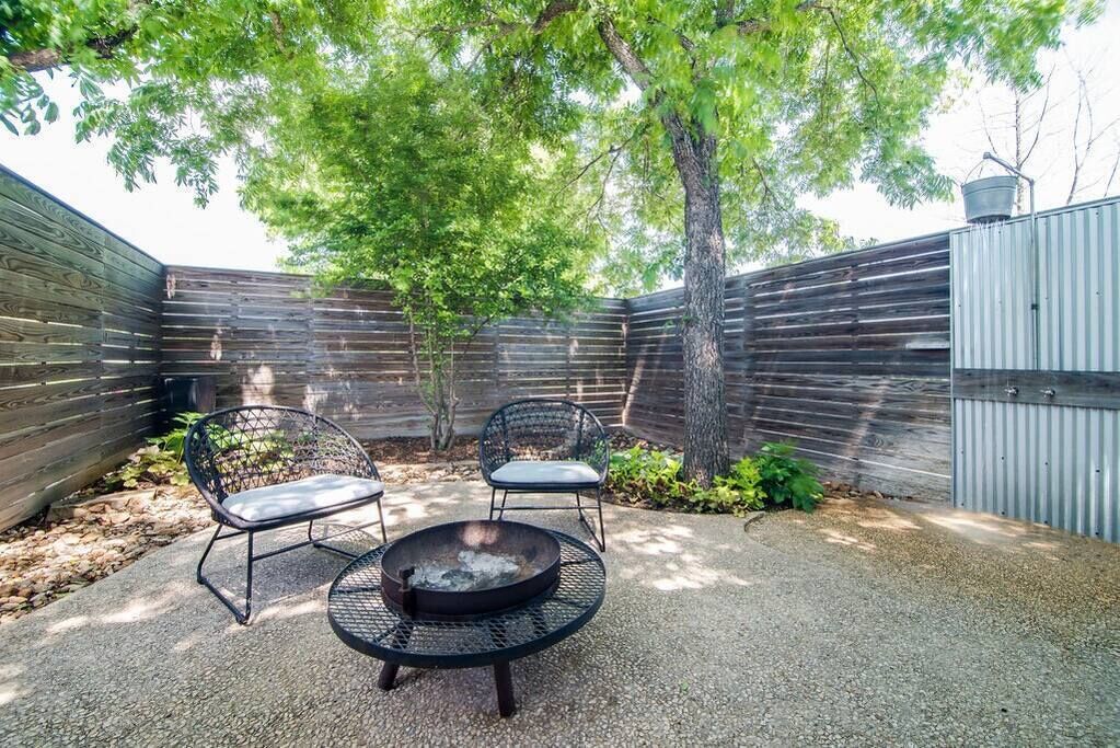 A patio area with two metal chairs, a round table, and a fire pit.