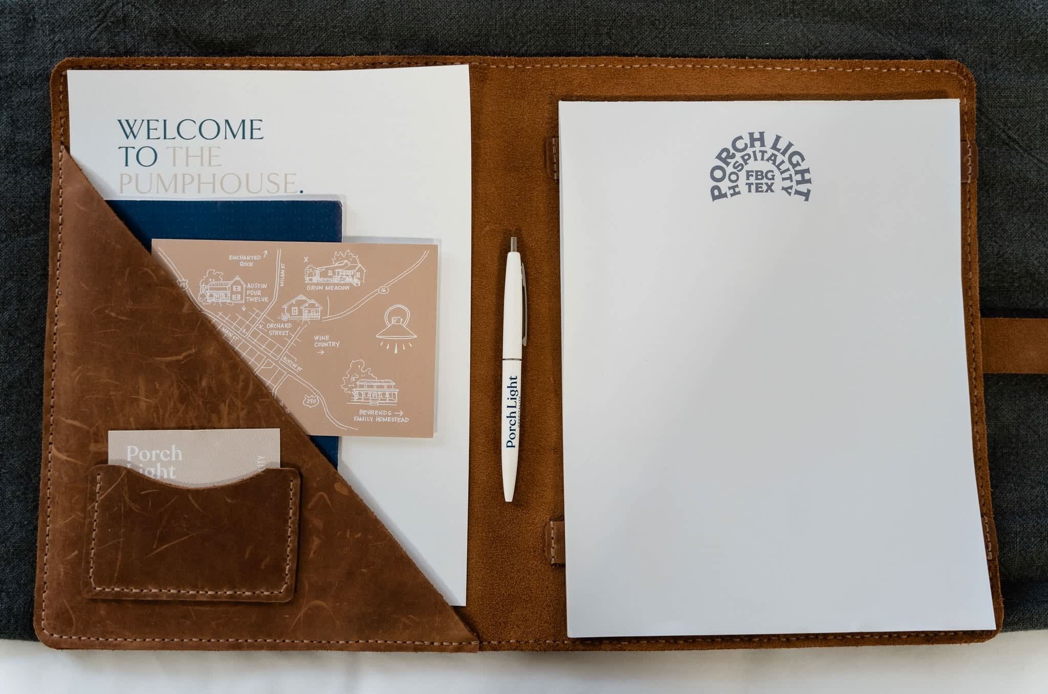 Un cuaderno de cuero con una nota de bienvenida, un mapa y una pluma.