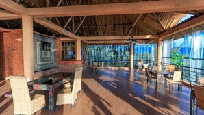 An open-plan restaurant with high ceilings, exposed beams, and a view of the sea through large windows. - Hakuna Matata Lodge (Gisenyi)