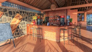 A bar area with a brick counter, stools, and a stone wall. - Hakuna Matata Lodge (Gisenyi)