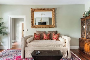 A living room with a sofa, a coffee table, a mirror, and a cabinet. - The Washington Square Collection (Savannah)