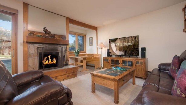 Una sala de estar acogedora con chimenea, sofás de cuero, una mesa de centro y un televisor que muestra 'YELLOWSTONE'.