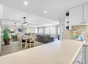 A spacious kitchen with a dining area, a built-in island, and a seating area with a sofa and chairs.