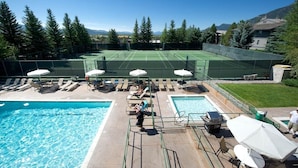 A pool area with a tennis court, lounge chairs, and umbrellas. - JHRL - Uncle Al's Timber Ridge 1 townhome, steps from Moose Creek lift (Teton Village)