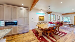 Una cocina moderna con electrodomésticos integrados, una zona de comedor con mobiliario de madera y amplias ventanas que ofrecen luz natural.