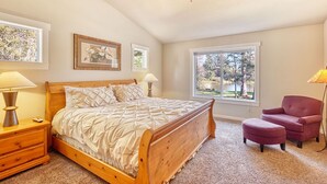 A bedroom with a wooden bed, two bedside lamps, a ceiling fan, a window with a view of trees, and a pink chair. - Amazing Lake View, Dogs Ok, UNIVERSAL EV CHARGER, Hot Tub, Kayaks (Lake) (Ocean Park)