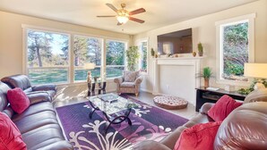 A living room with a leather sofa, a glass coffee table, a fireplace, and large windows with a view of trees. - Amazing Lake View, Dogs Ok, UNIVERSAL EV CHARGER, Hot Tub, Kayaks (Lake) (Ocean Park)
