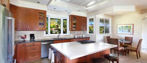 Una cocina amplia con armarios de madera, una isla grande con taburetes y un comedor con mesa y sillas.