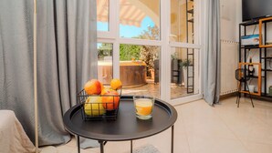 Une pièce avec une table à manger, un panier de fruits et un verre de jus d’orange.