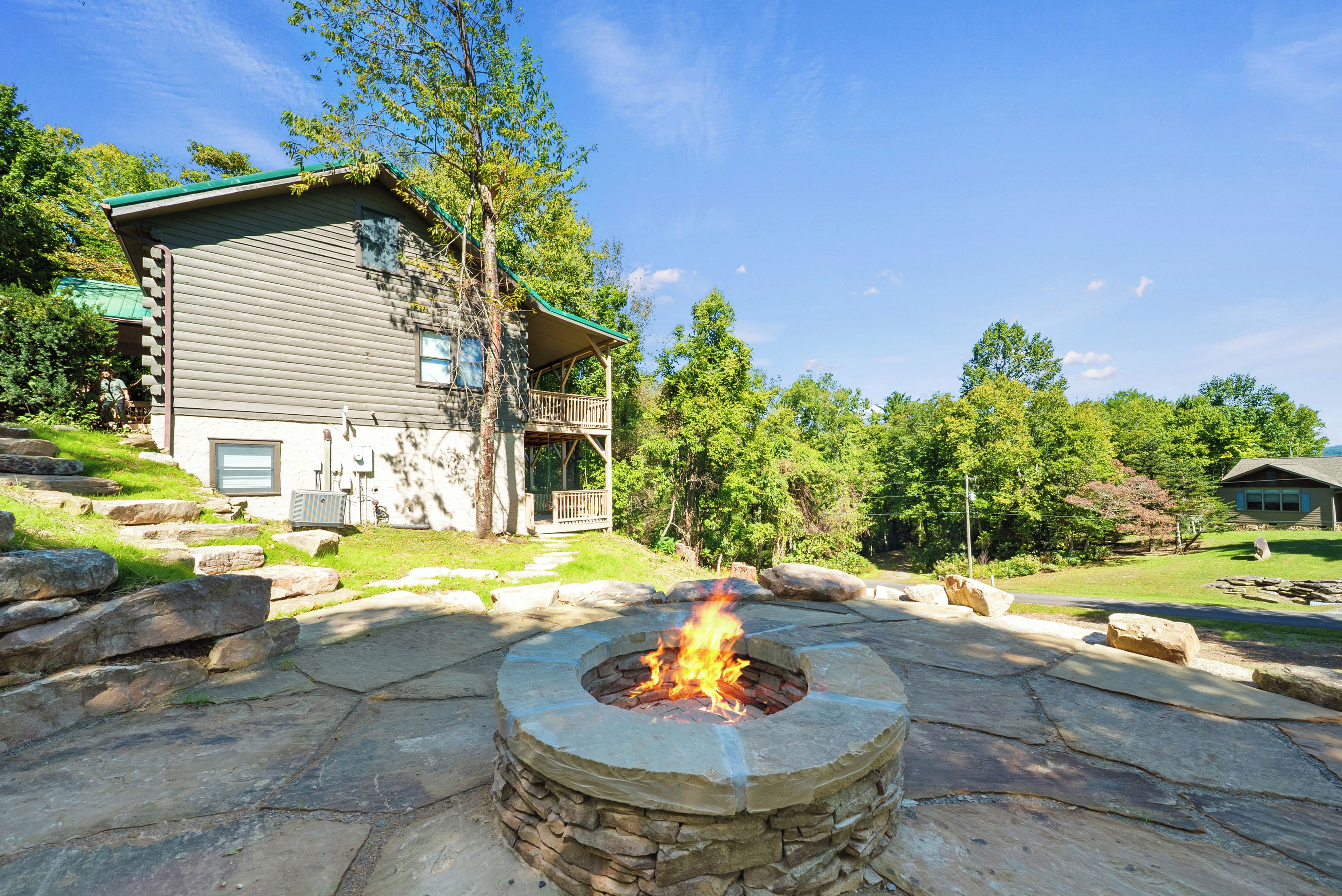 A stone fire pit in the foreground with a house in the background.