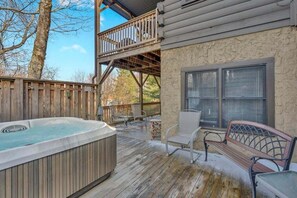 Eine Holzdielen-Terrasse mit Whirlpool, Sitzgelegenheit und Blick auf Baum und Himmel.