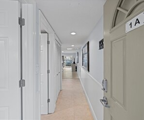 Stylish corridor with framed artwork and modern door handles leads to a room with an outside view.